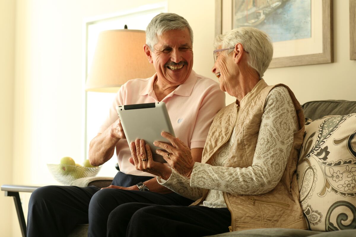 an elderly couple using a tablet and smiling