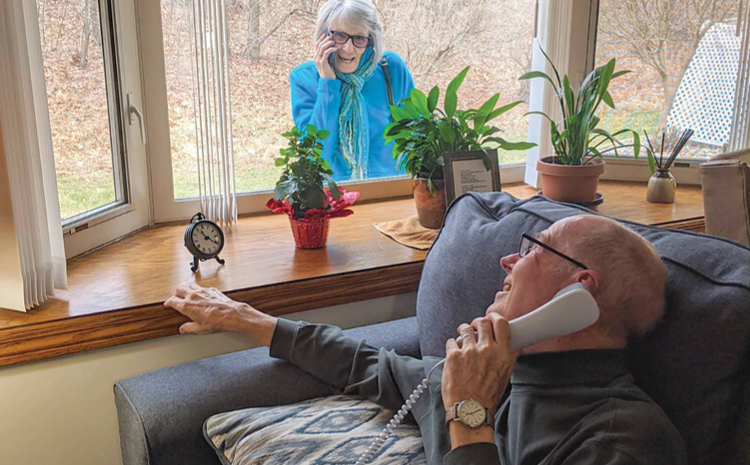 an elderly woman calling an elderly man from outside the window