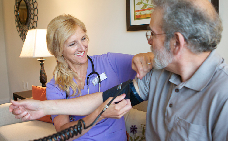 a worker checking an older man's blood pressure