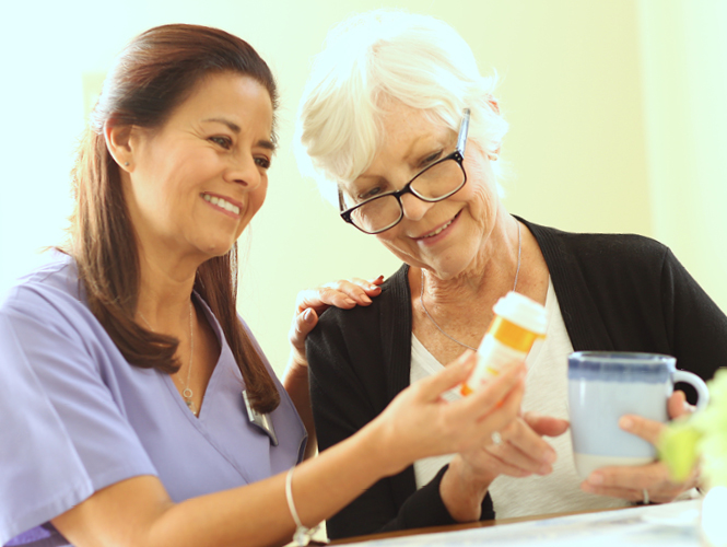 young female healthcare worker assists senior man in his kitchen