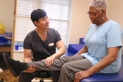 male therapist assists senior female with rehab exercise