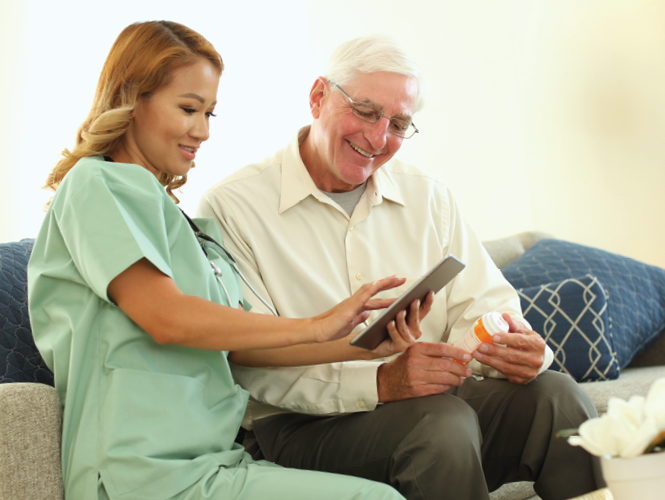 young female cna uses iPad to teach senior man about his medication