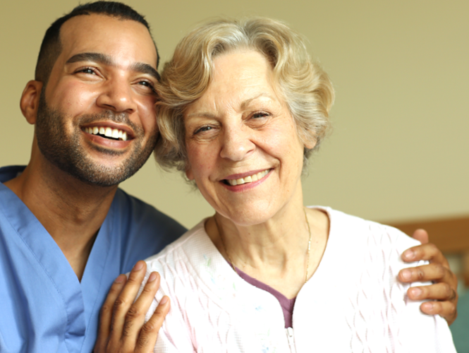 Male home healthcare worker smiles with senior woman