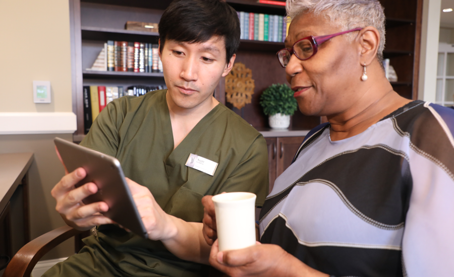 male healthcare manager uses iPad to discuss treatment plan with senior woman