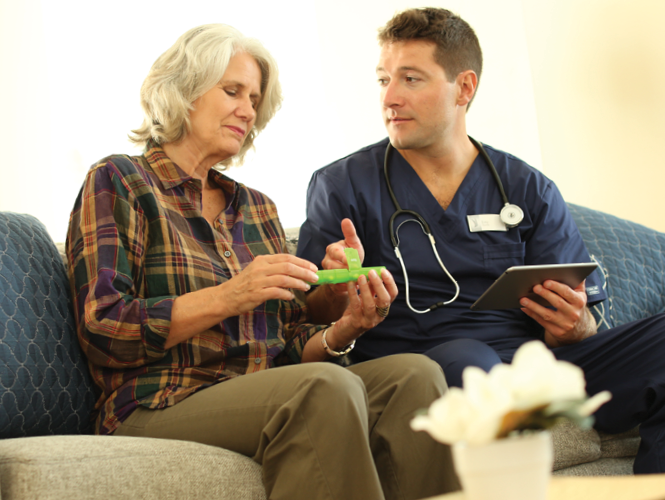 senior woman holds pill box and asks young male cna about medicine