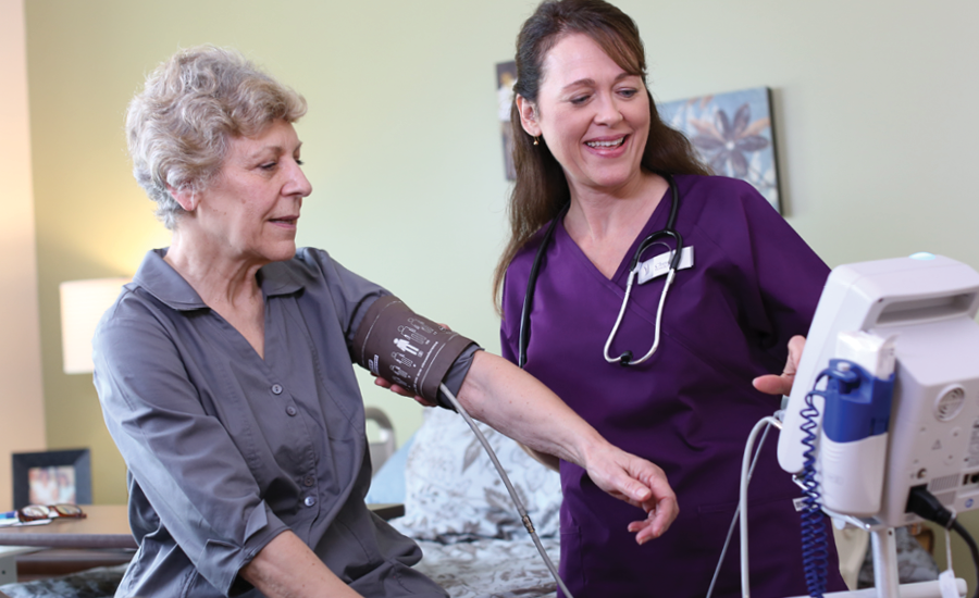 cna takes vital signs of female nursing home resident