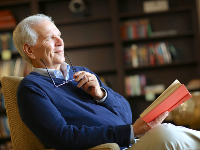 an older man in the study reading a book