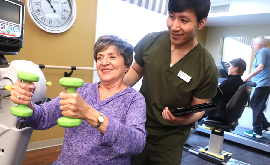 female park place resident works in gym with male senior fitness instructor