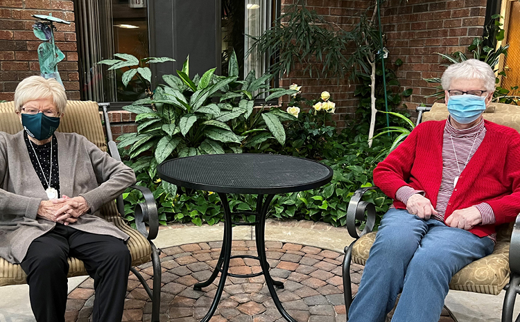 two elderly women sitting and wearing surgical masks