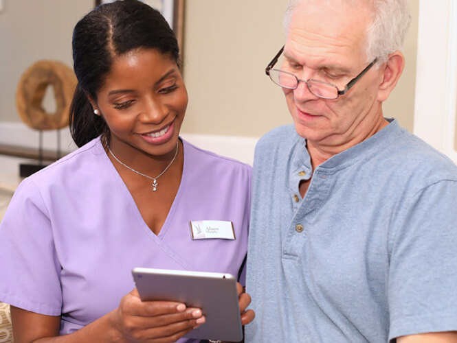 a female CNA showing an elderly man care plan on an ipad