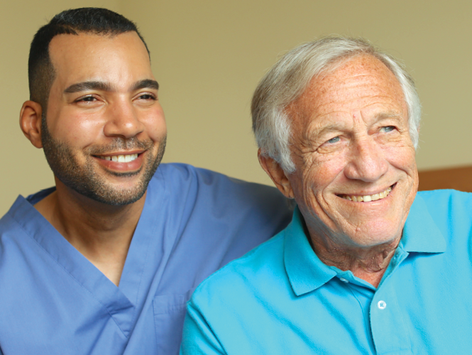 a healthcare working with and elderly man smiling