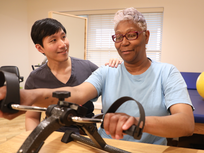 a male CNA assist a senior female rehab patient