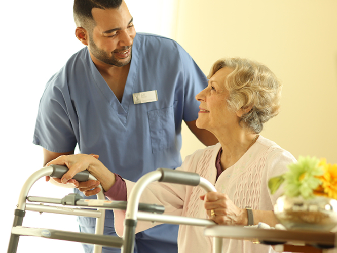 A male cna assists senior resident with using walker