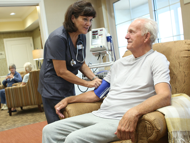 a female healthcare worker takes vitals of senior male patient