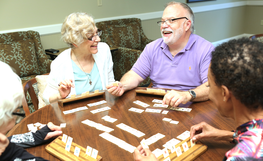 table of royal park place resident laugh together as they place rummikub