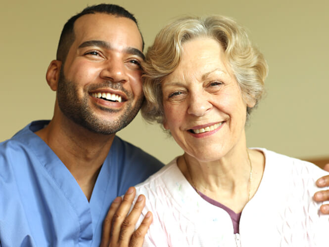 a male CNA and an elderly woman smiling