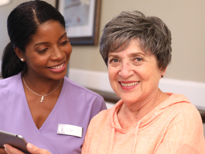 a female CNA and a senior respite client smile together