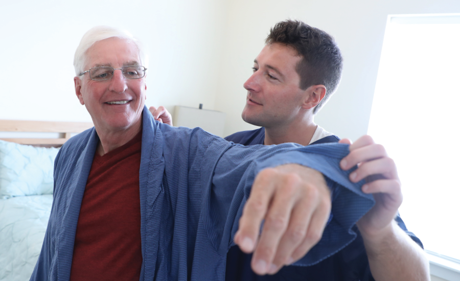 male cna assists transition to home patient with his robe