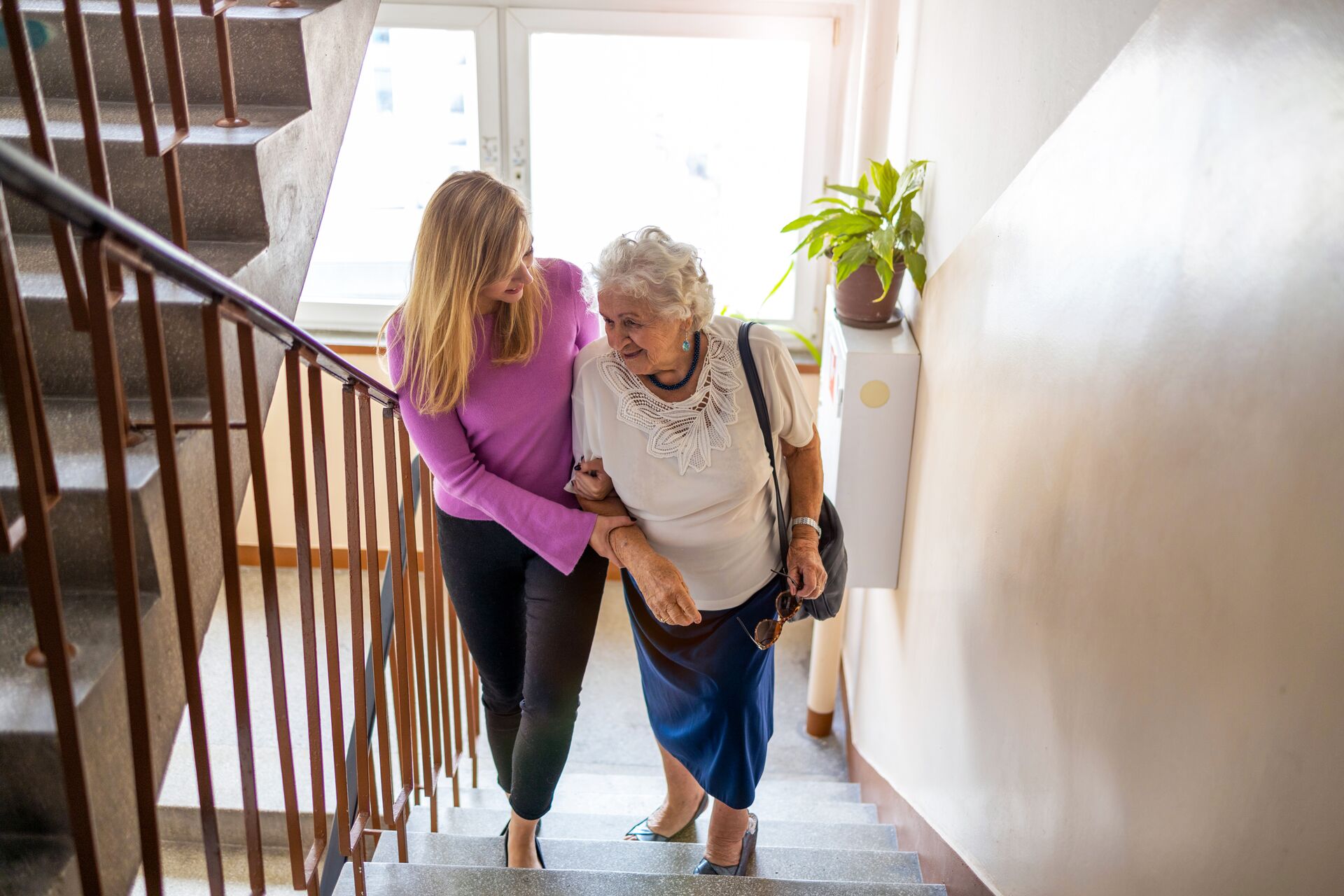 a woman helping her mother up the stairs