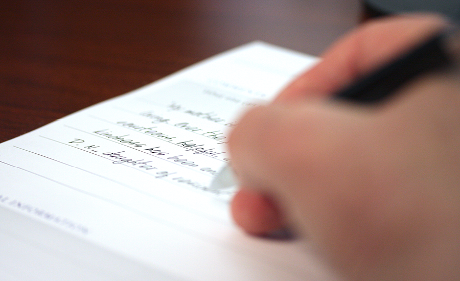 close up of woman's hand writing victorian village testimonial