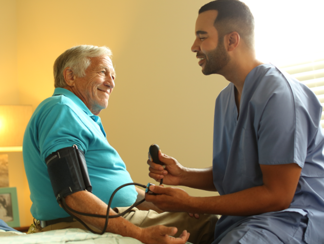 young male healthcare worker takes senior man's blood pressure