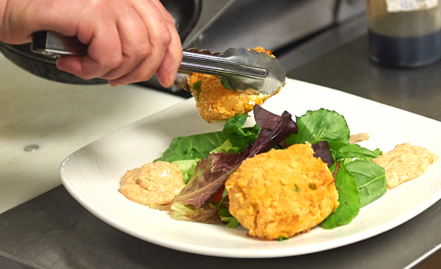 close up of chef's hands plating restaurant-quality meal at royal park place