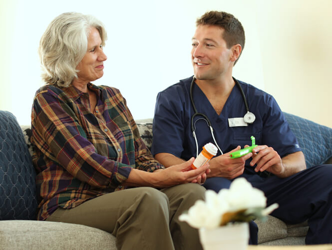 a male CNA explaining medication to an elderly woman