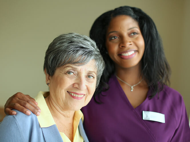 a female resident aide and an elderly woman smiling