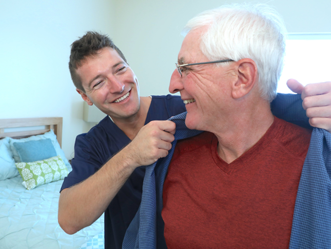 a healthcare worker helping an elderly man with his jacket