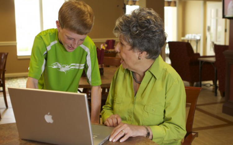 a grandson showing his grandma how to use her laptop