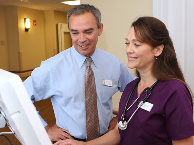 a male doctor a female nurse looking at something on a computer screen in nursing home