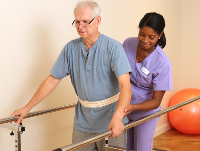 female therapist assists male senior patient with balance bars