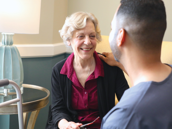 senior woman smiles and speaks to young male healthcare worker