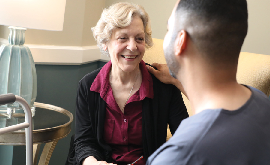 senior victorian village resident smiles with his assisted living resident aide