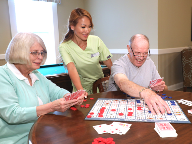 female resident aide assists senior residents playing sequence